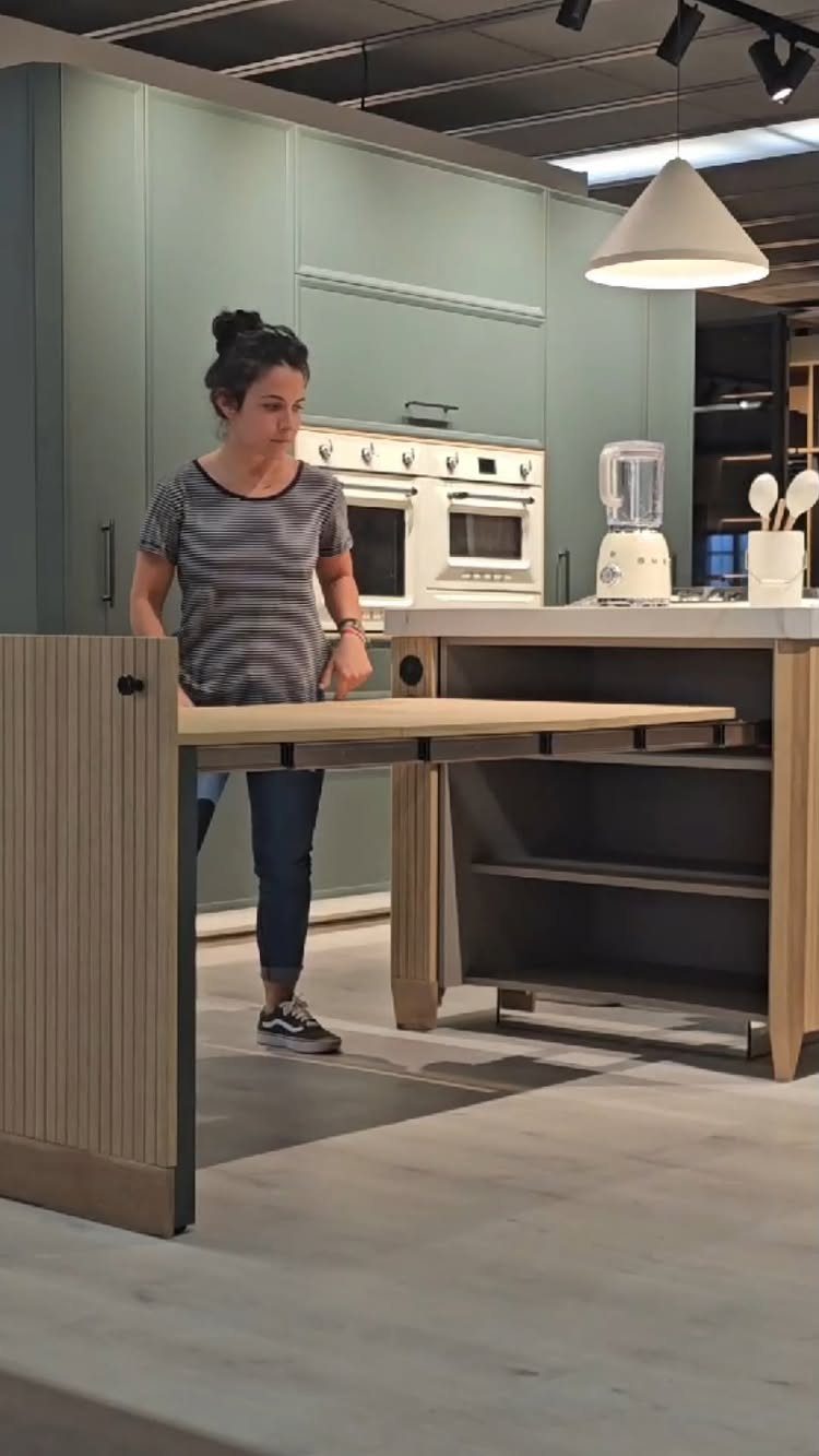 5 Modular Kitchen Table Designs for Flexible Dining Areas 4 Woman extending a light wood table surface from a grey kitchen island.