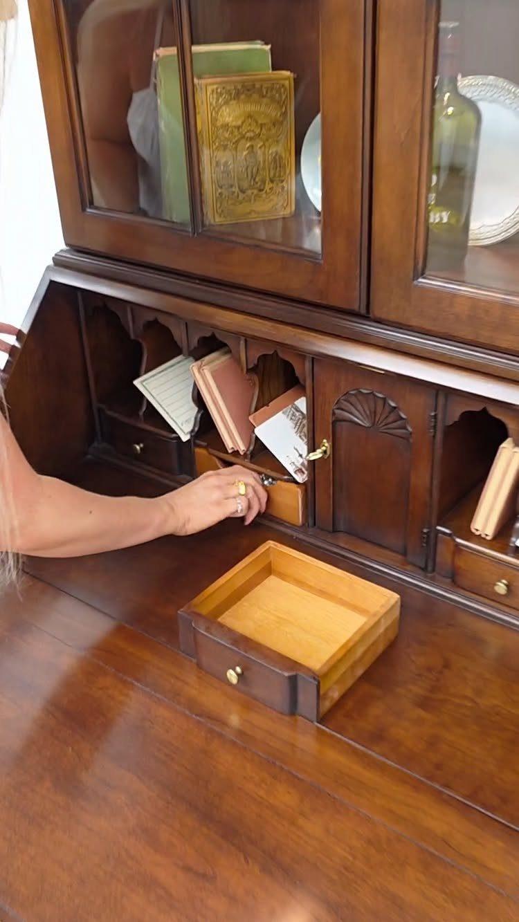 Antique secretary bookcase with a glass-door upper cabinet and open writing desk drawers.