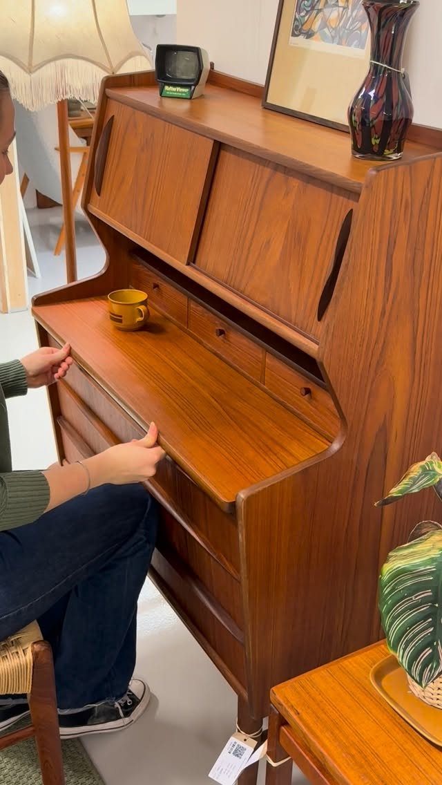 Mid-century modern wooden secretary desk with a person sitting at the writing surface.