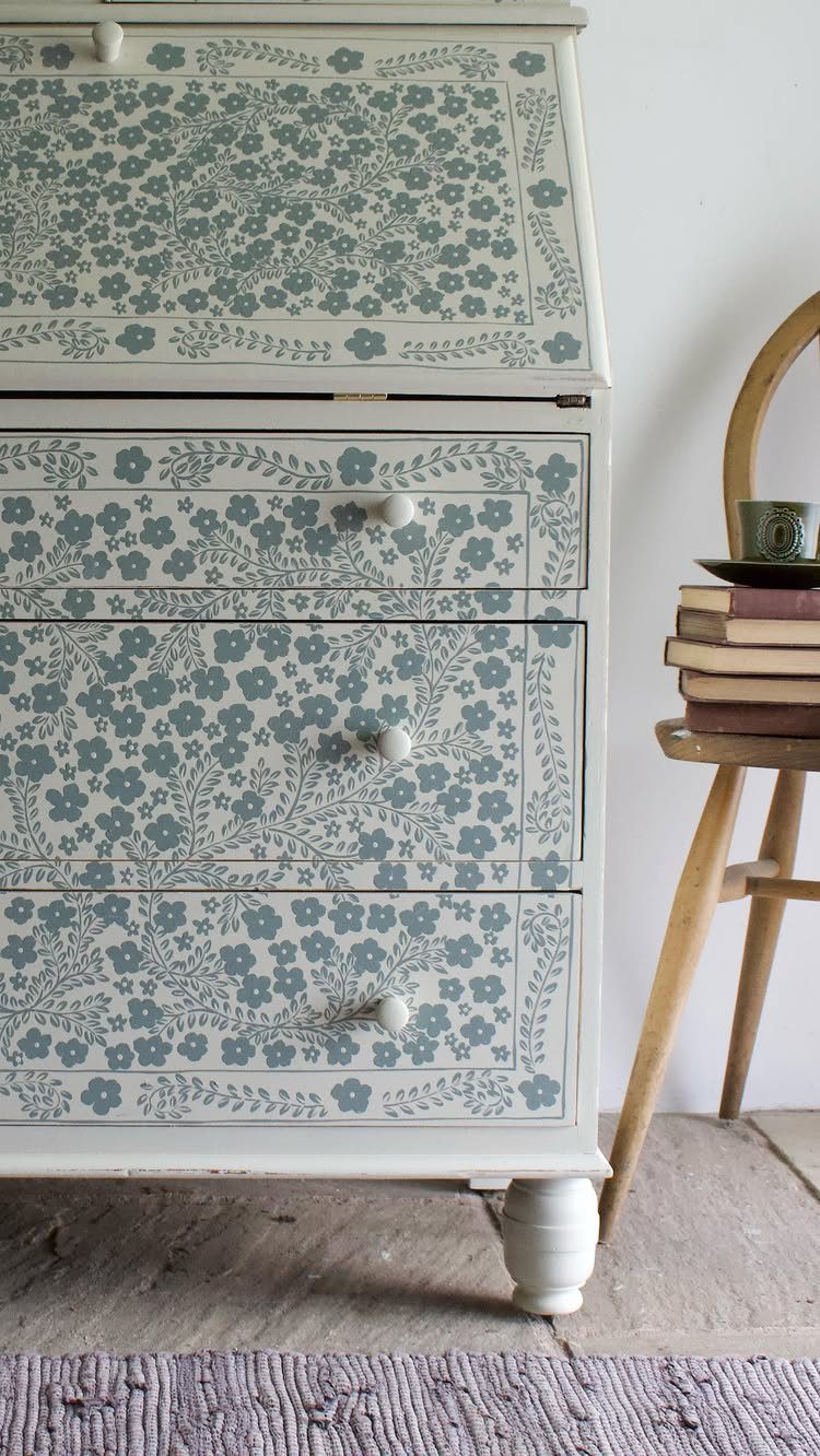 White secretary desk with blue floral painted patterns on the slant-front and drawers.