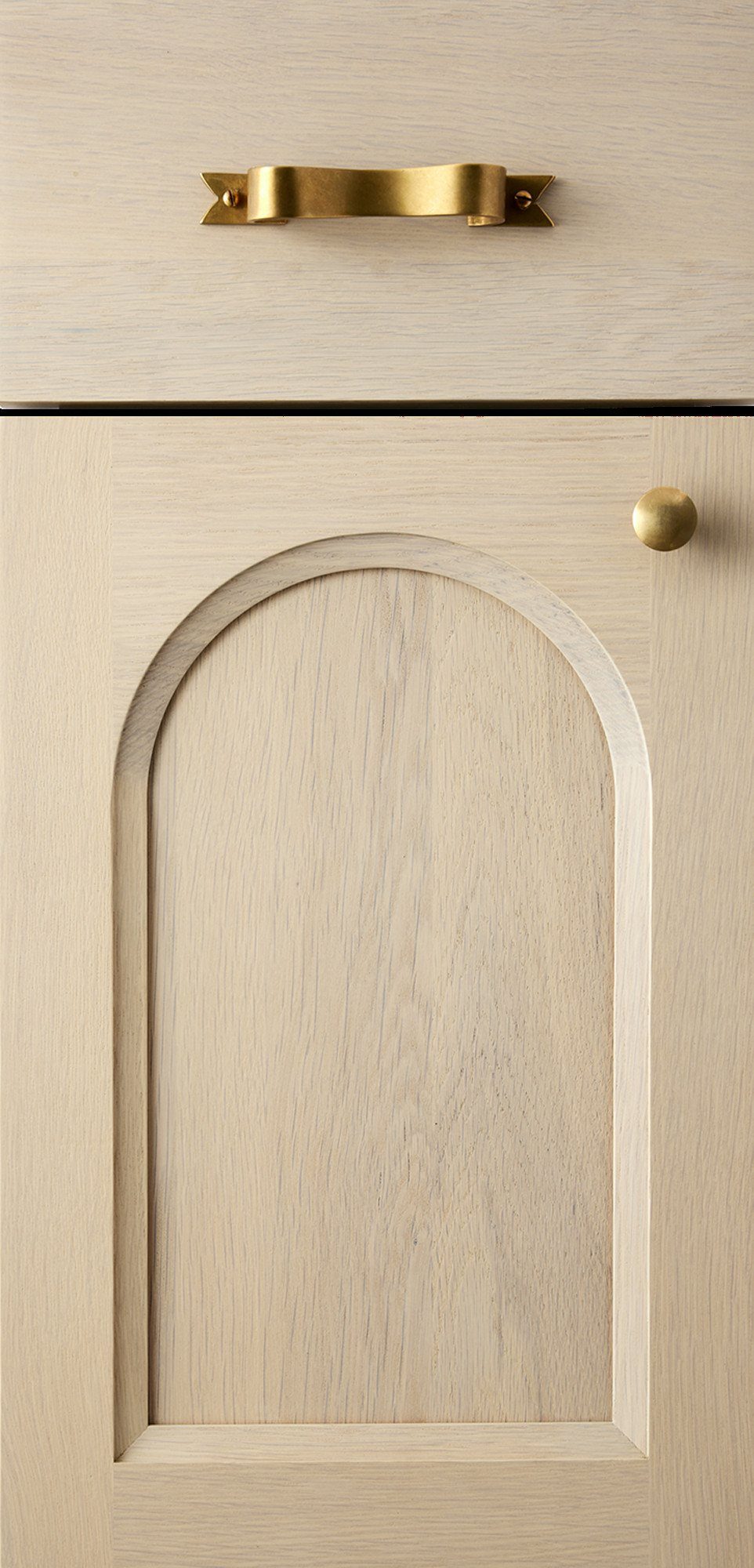 Light wood cabinet door with a recessed arched panel and gold hardware.
