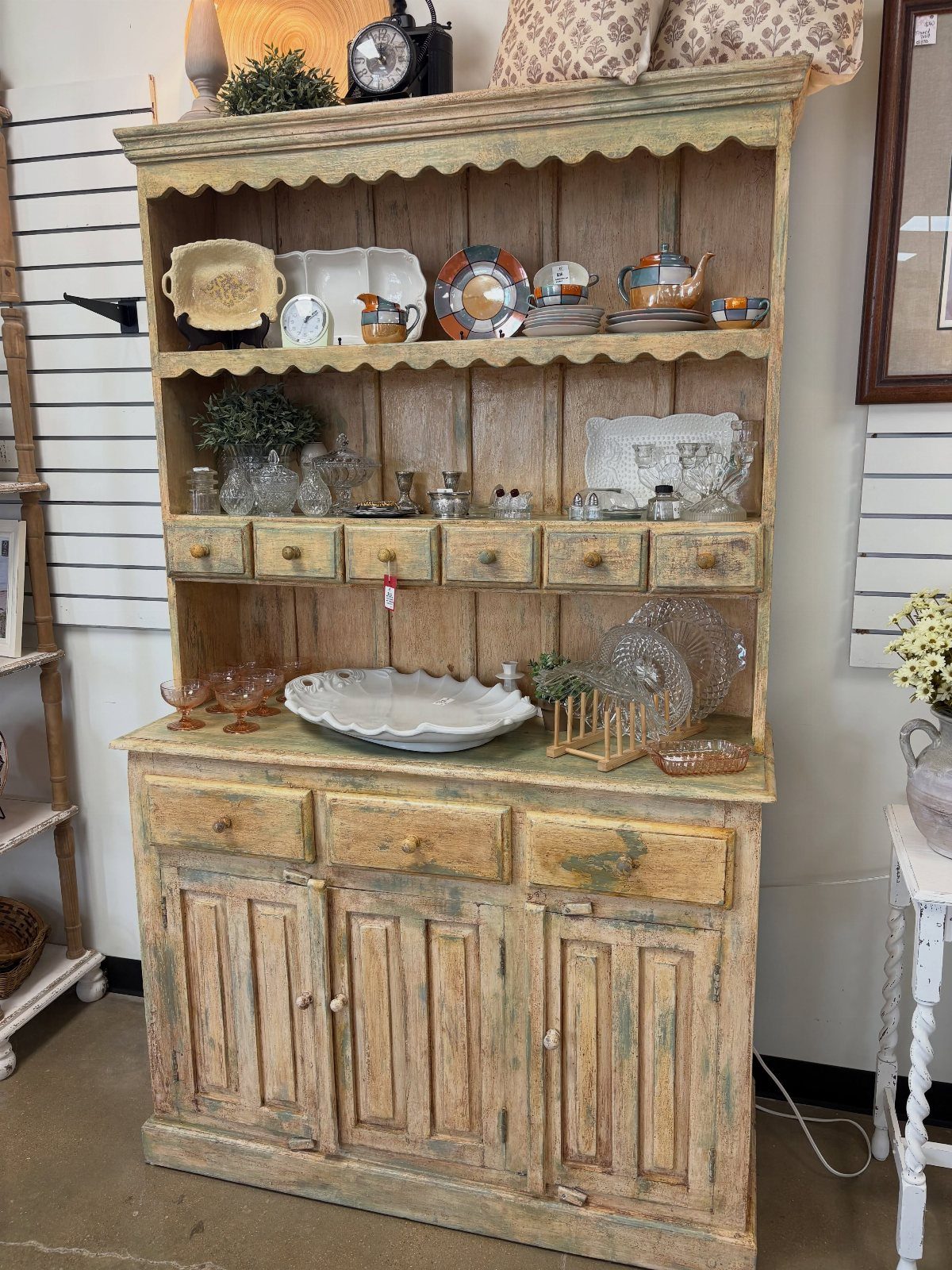 Rustic weathered wood hutch with open shelves, small drawers, and lower cupboards.
