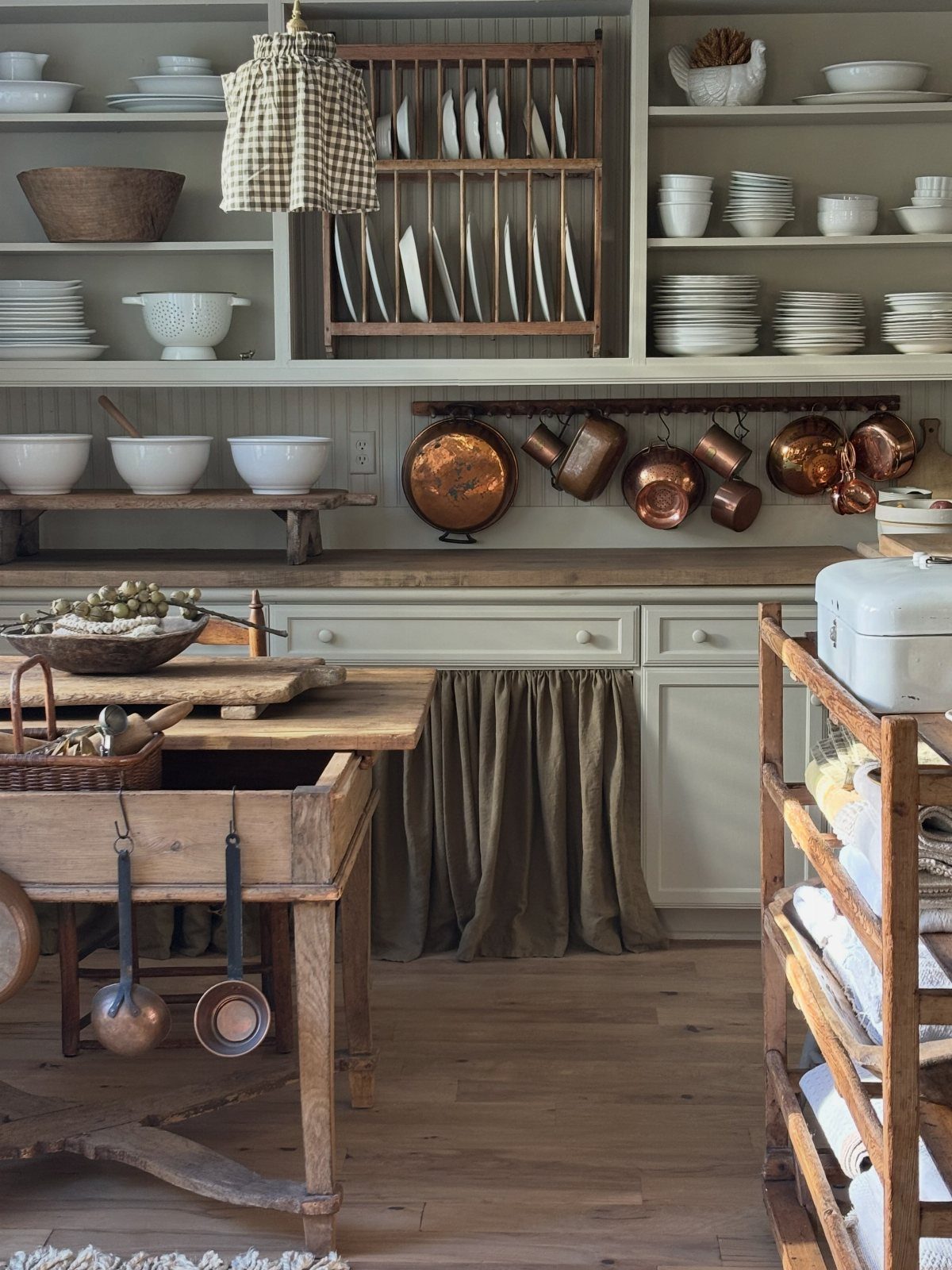 Built-in light grey farmhouse kitchen hutch with open shelving and hanging copper pots.