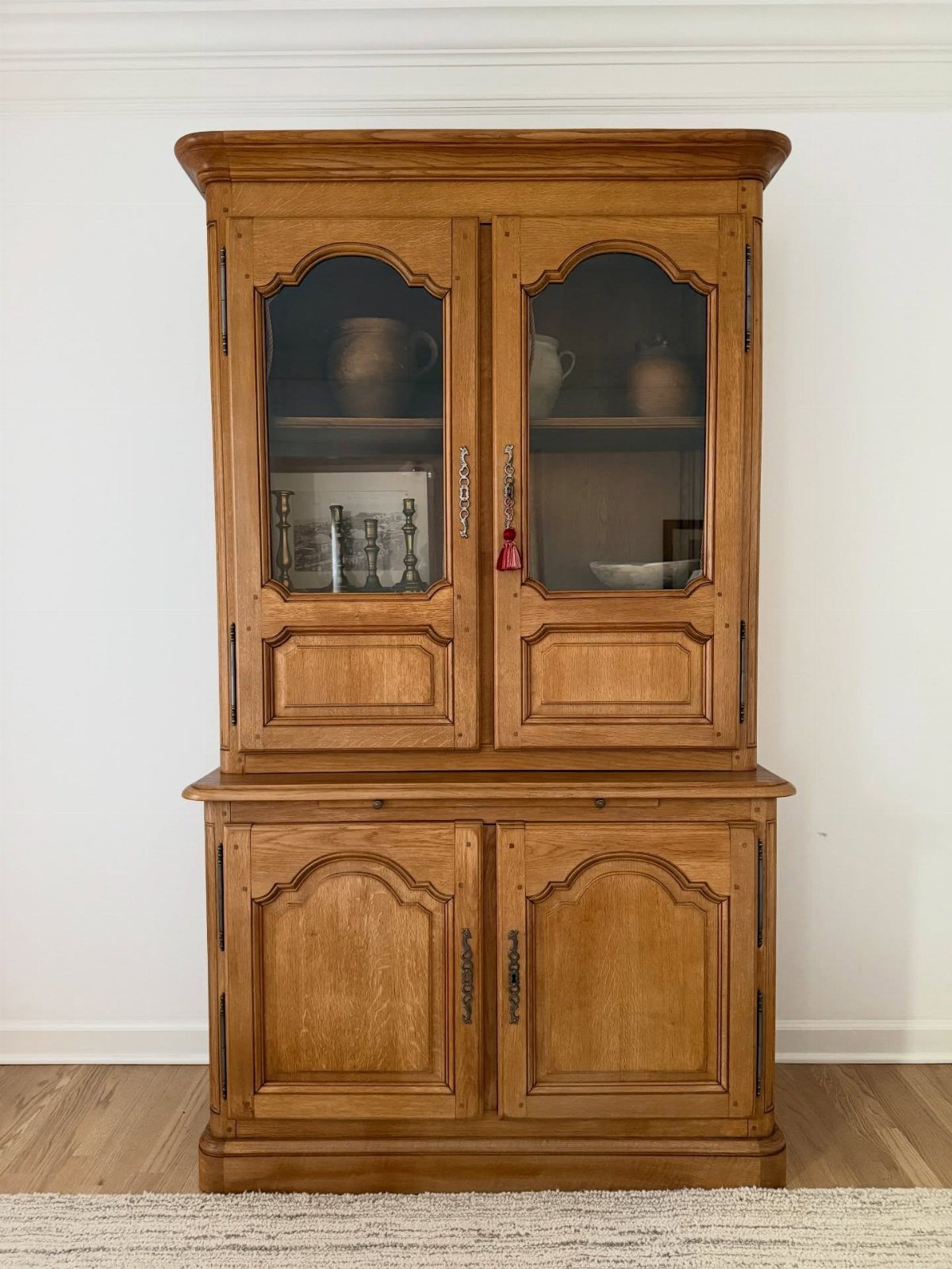 Light brown wood hutch with arched glass doors and a matching lower cabinet.