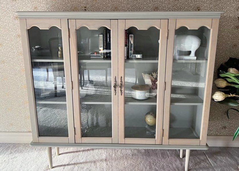 Light wood hutch with four glass-front doors and arched top panels.