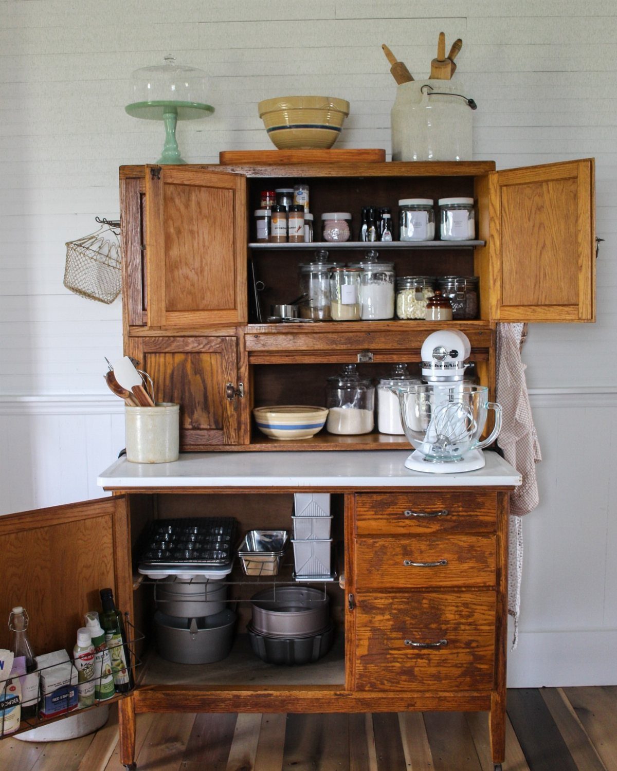 Vintage wooden Hoosier cupboard with a white countertop and pull-out mixing tray.
