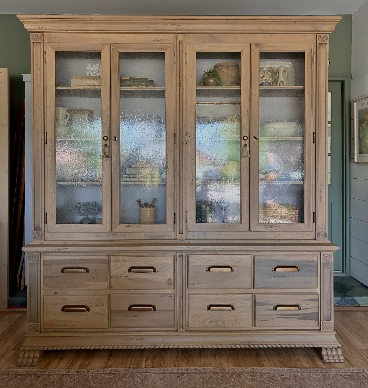 Light wood hutch with glass-front upper cabinets and interior glass shelves.