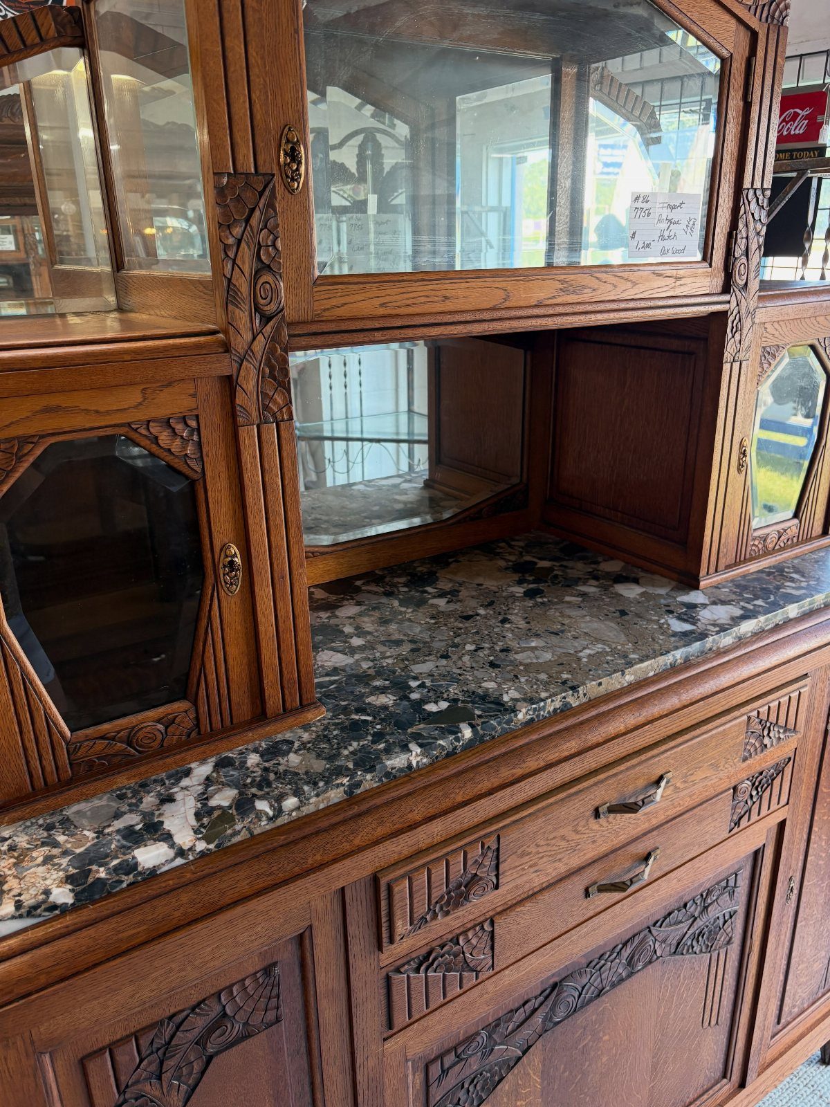 Dark brown carved wood hutch with a granite countertop and glass cabinets.