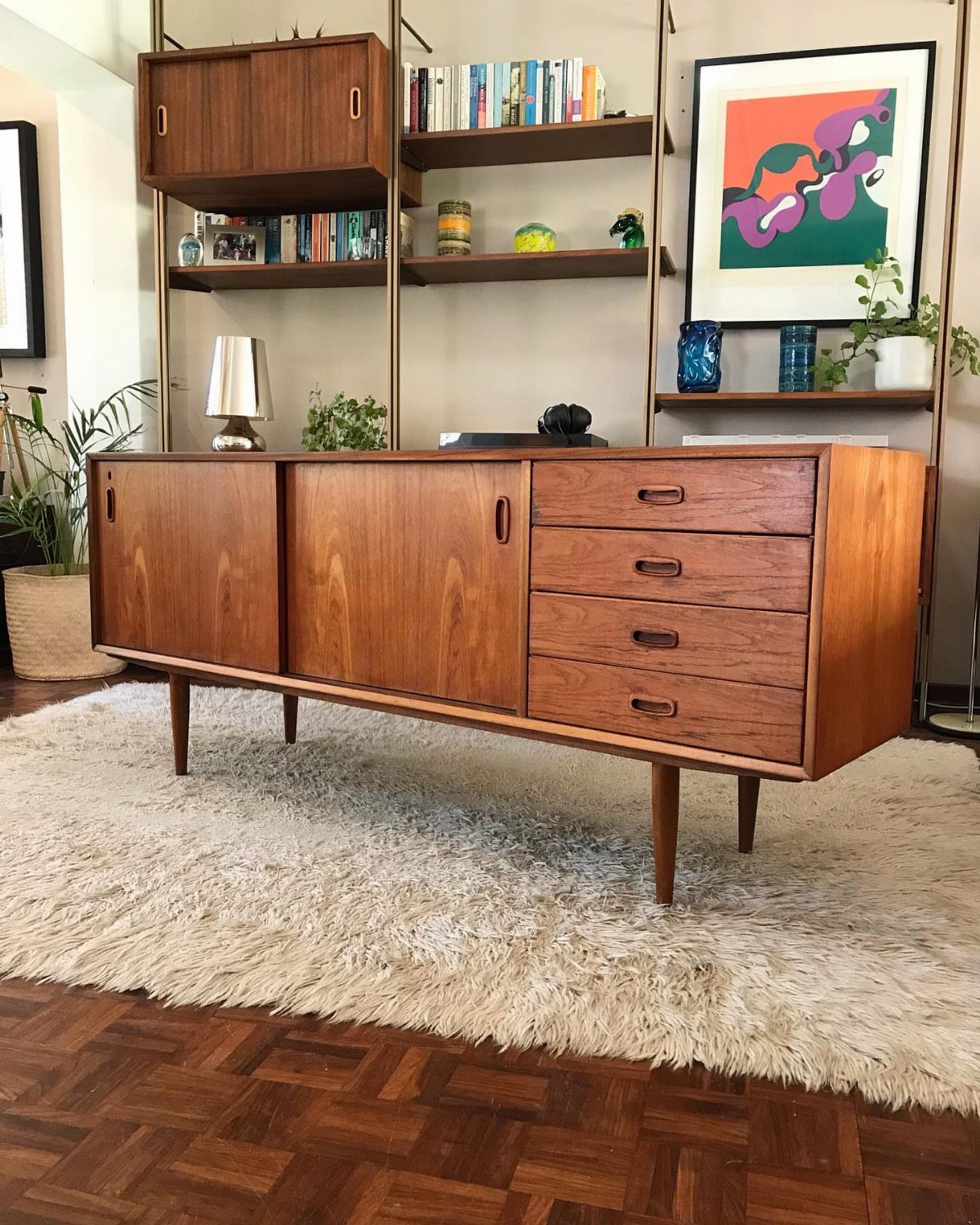 Scandinavian teak sideboard with sliding doors and drawers on a white shag rug.