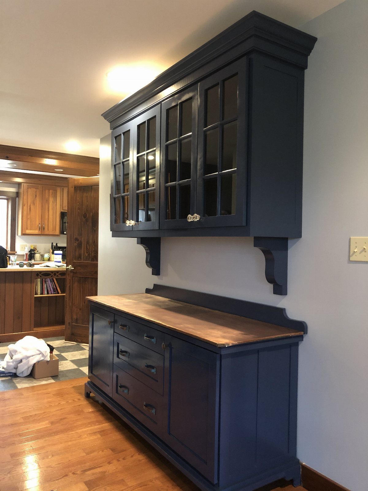 Navy blue painted hutch with a natural wood countertop and glass-front upper cabinets.