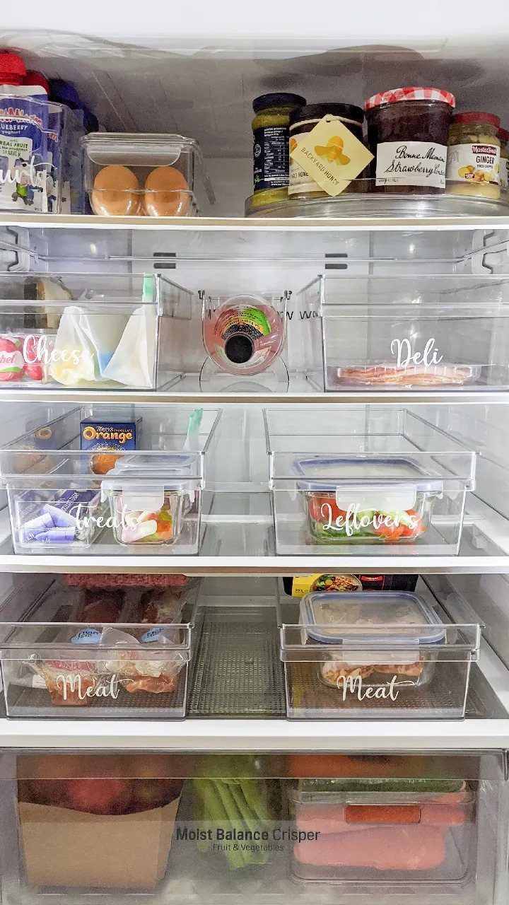 Clear plastic refrigerator bins with white cursive labels for meat, deli, and leftovers.