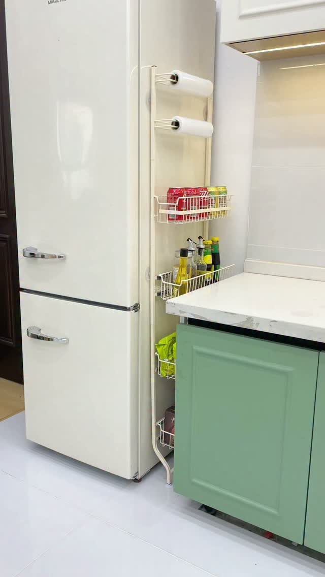 White refrigerator with a slim metal storage rack holding condiments and paper towels.