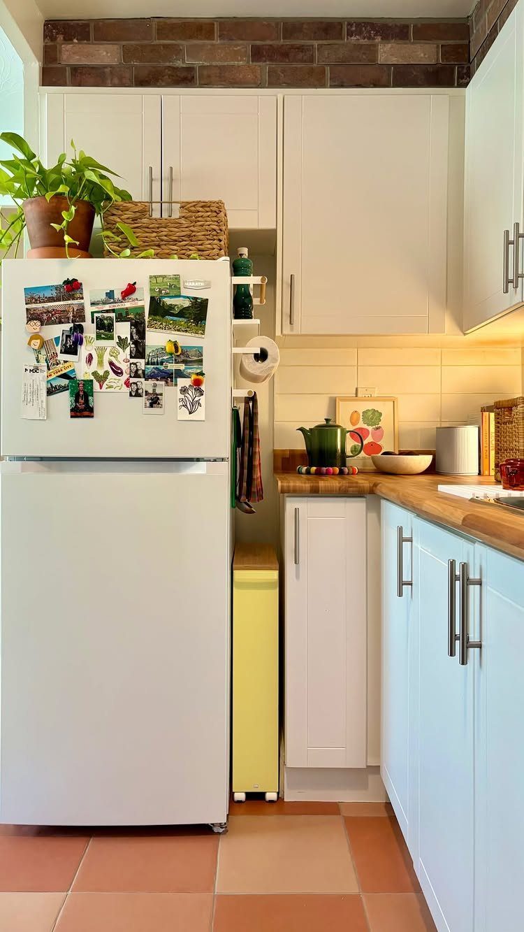 White refrigerator with a woven basket and potted plant stored on top.
