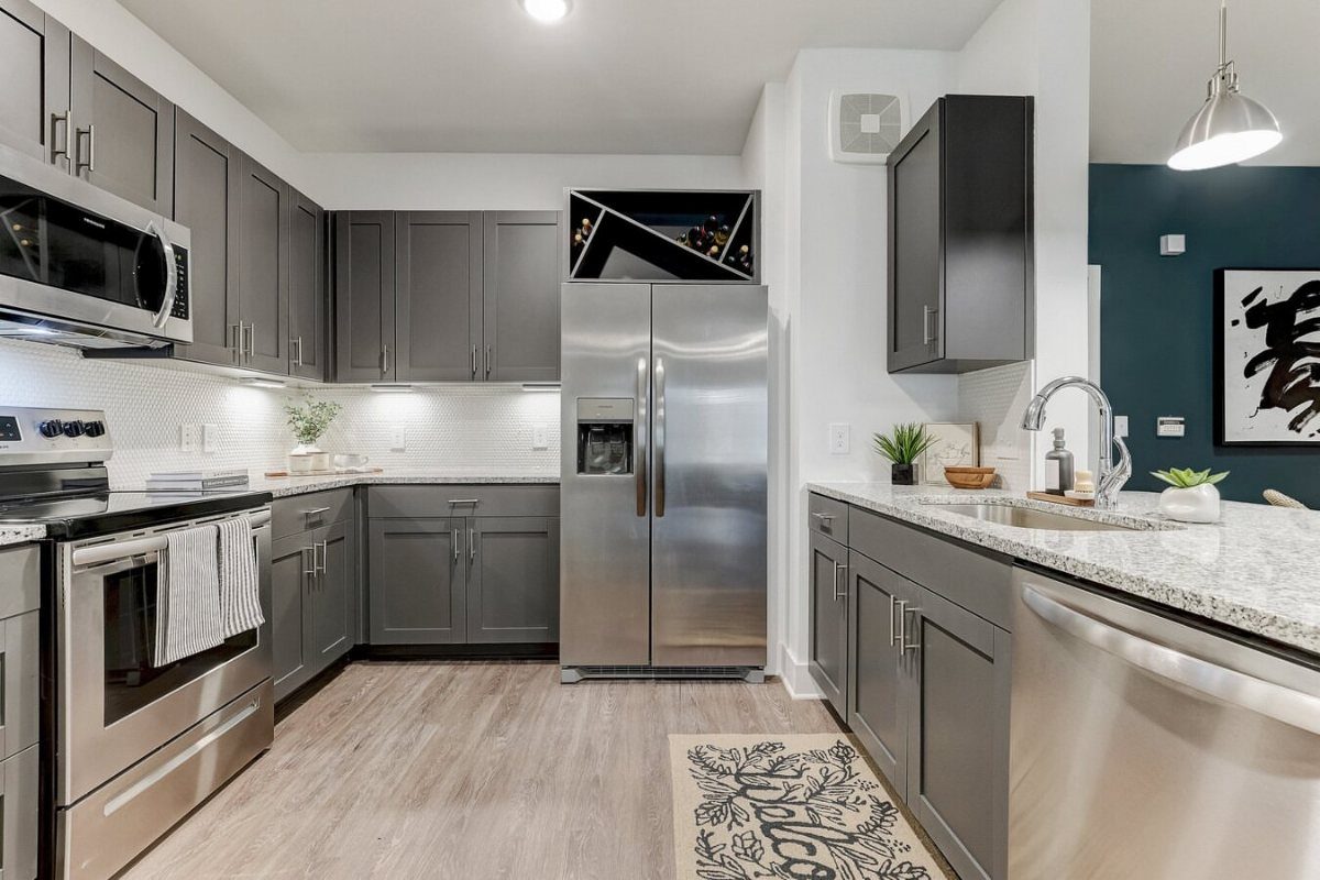 Built-in wine rack holding bottles located in a cabinet above a stainless steel refrigerator.