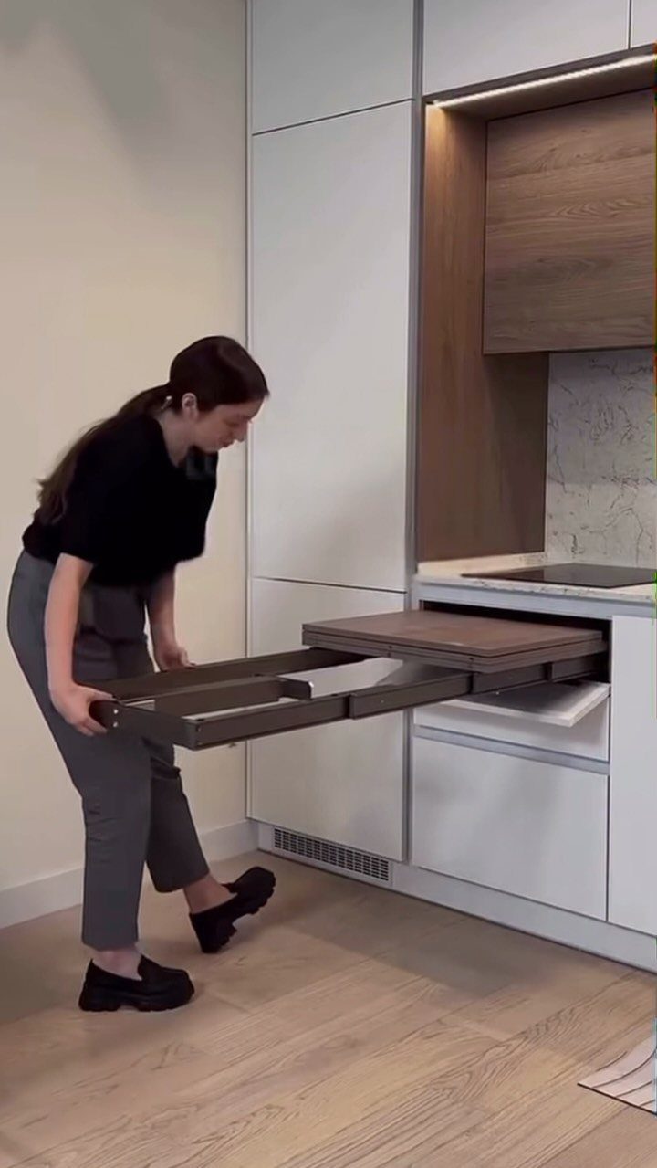 Pull Out Counter Ideas: 8 Ways to Add Kitchen Work Space 9 Woman pulling out a sliding wooden counter extension from white kitchen cabinetry.