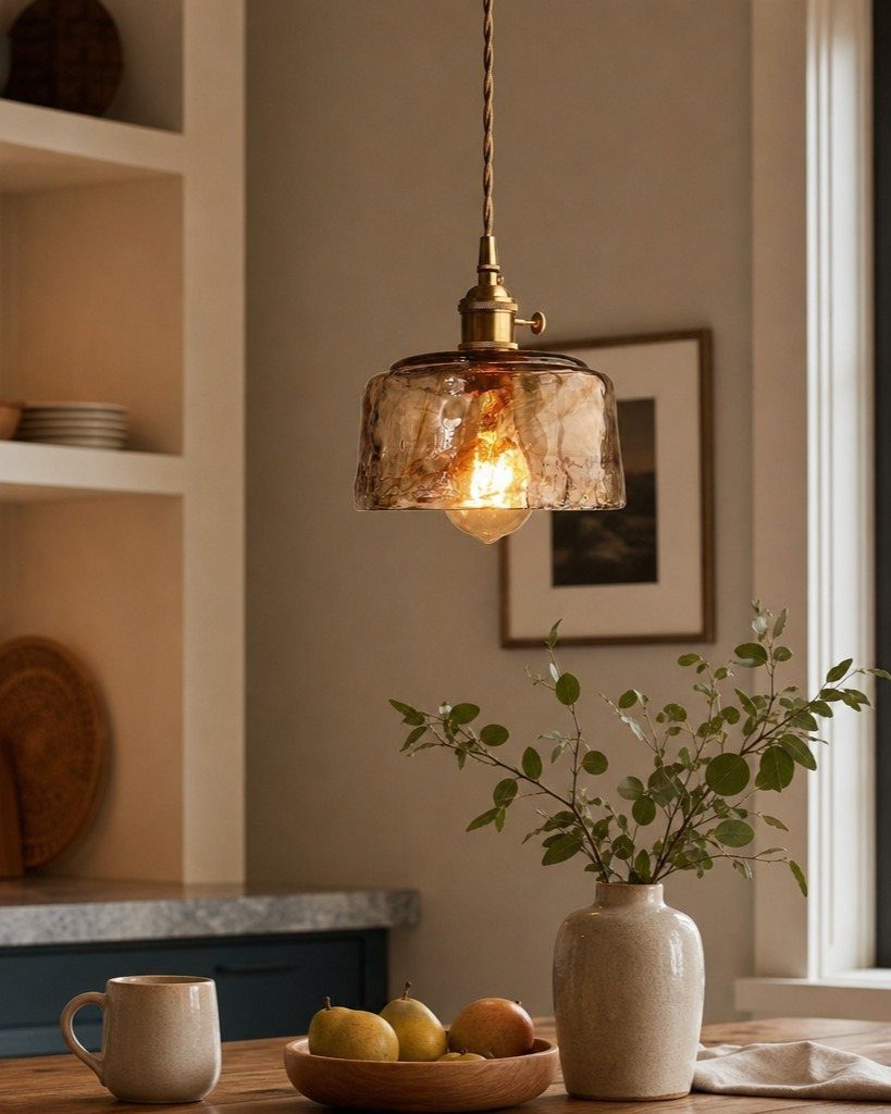 19 Small Kitchen Reno Ideas That Maximize Every Inch 13 Amber glass pendant light hanging over a wooden table with fruit and greenery