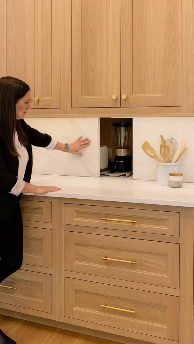 19 Small Kitchen Reno Ideas That Maximize Every Inch 17 Woman sliding a white panel to hide a blender in a kitchen backsplash.
