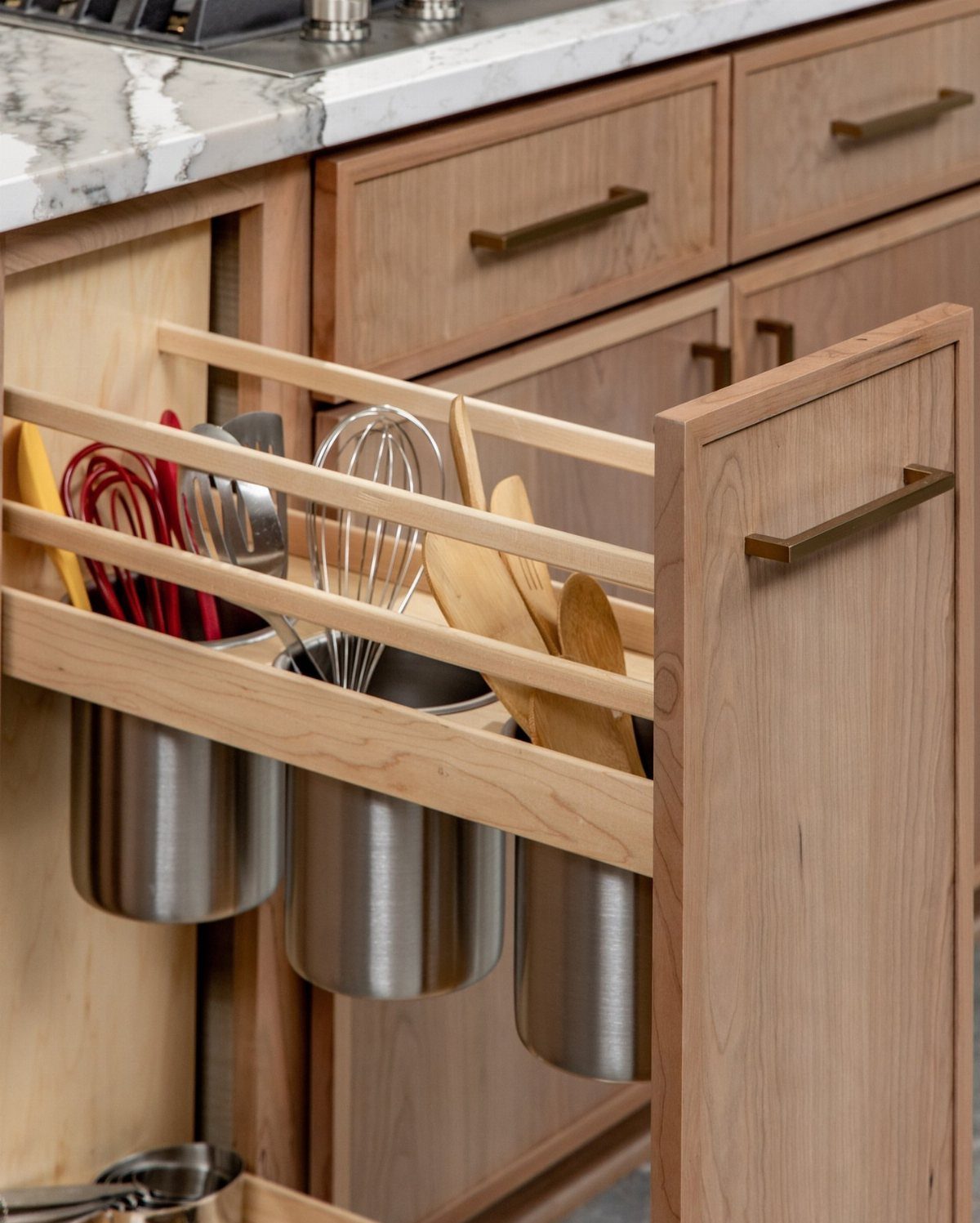 19 Small Kitchen Reno Ideas That Maximize Every Inch 14 Inside-cabinet-door basket holding stainless steel canisters with whisks and wooden kitchen utensils.