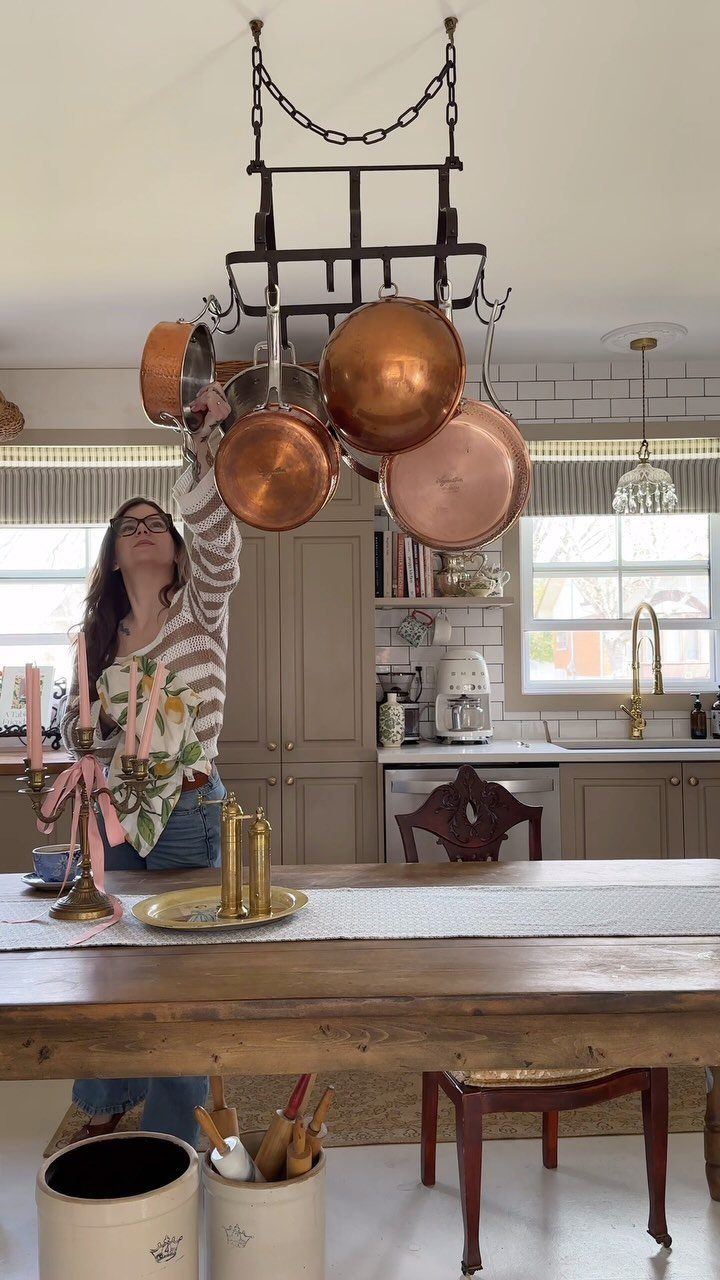 19 Small Kitchen Reno Ideas That Maximize Every Inch 6 Copper pots hanging from a black metal ceiling rack in a kitchen.