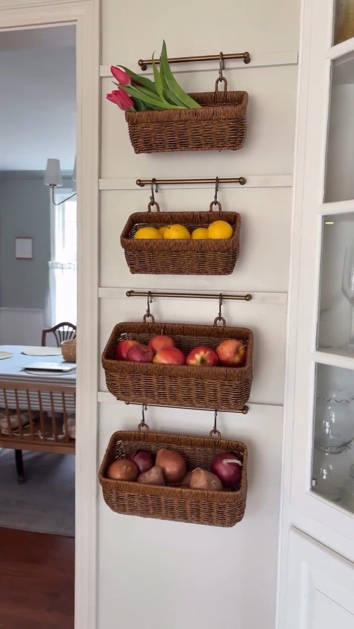 19 Small Kitchen Reno Ideas That Maximize Every Inch 12 Wicker baskets hanging on a white wall holding fruit and flowers in a kitchen.