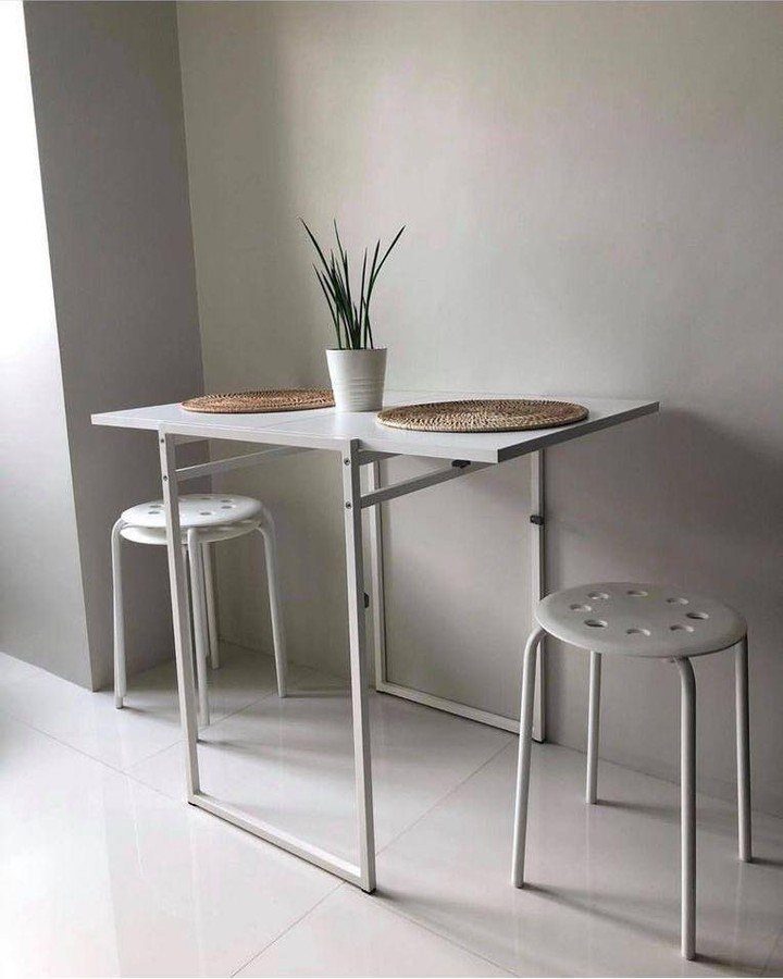 White folding table with two white stools and a small potted plant.