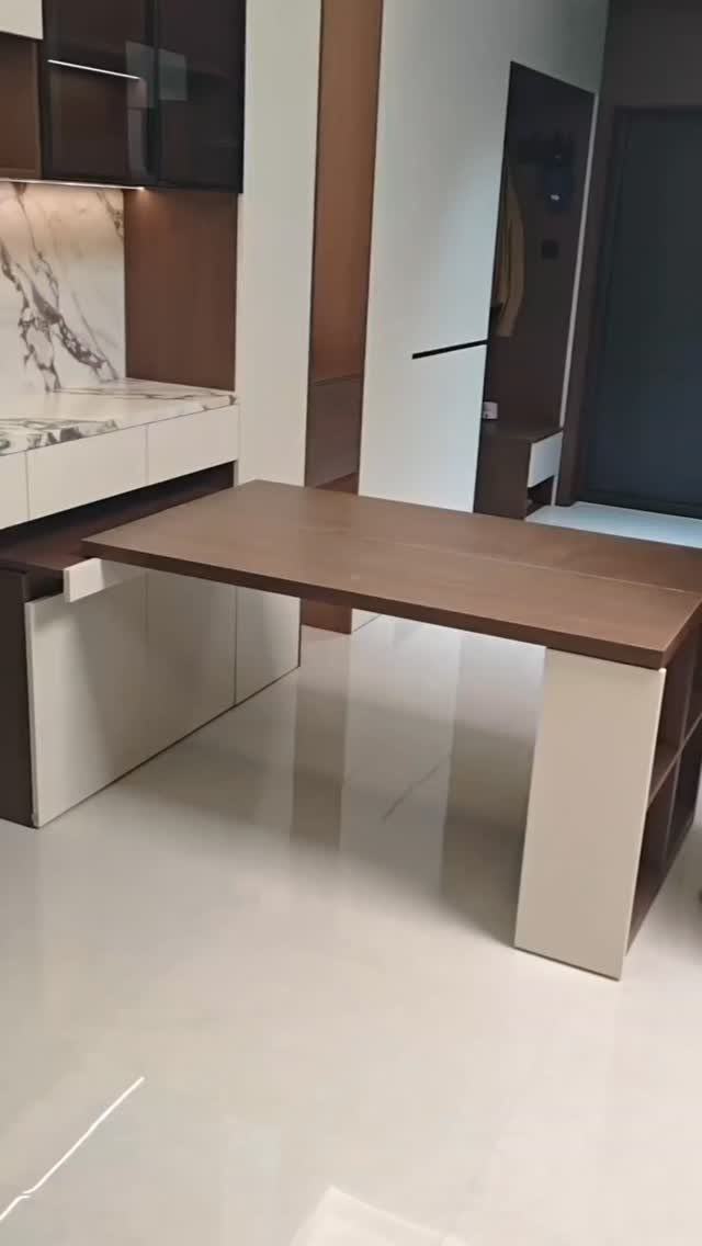 Brown wooden pull-out table extending from a white kitchen cabinet in a modern room.