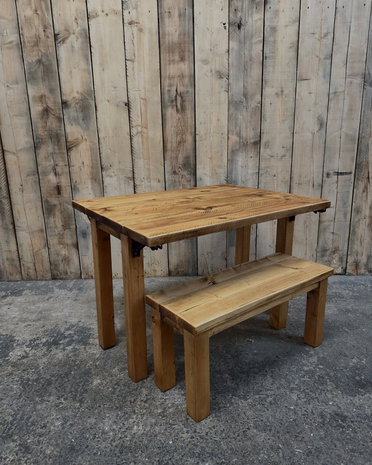 Rustic wooden dining table with a matching bench tucked underneath against wooden walls.