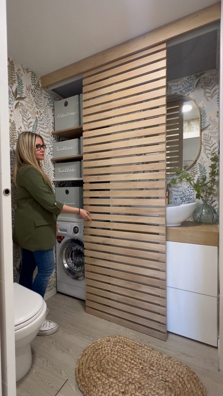 Tiny House Layout Ideas: 27 Smart Ways to Maximize Space 23 Woman standing in a small bathroom with a washing machine and wooden slat partition.