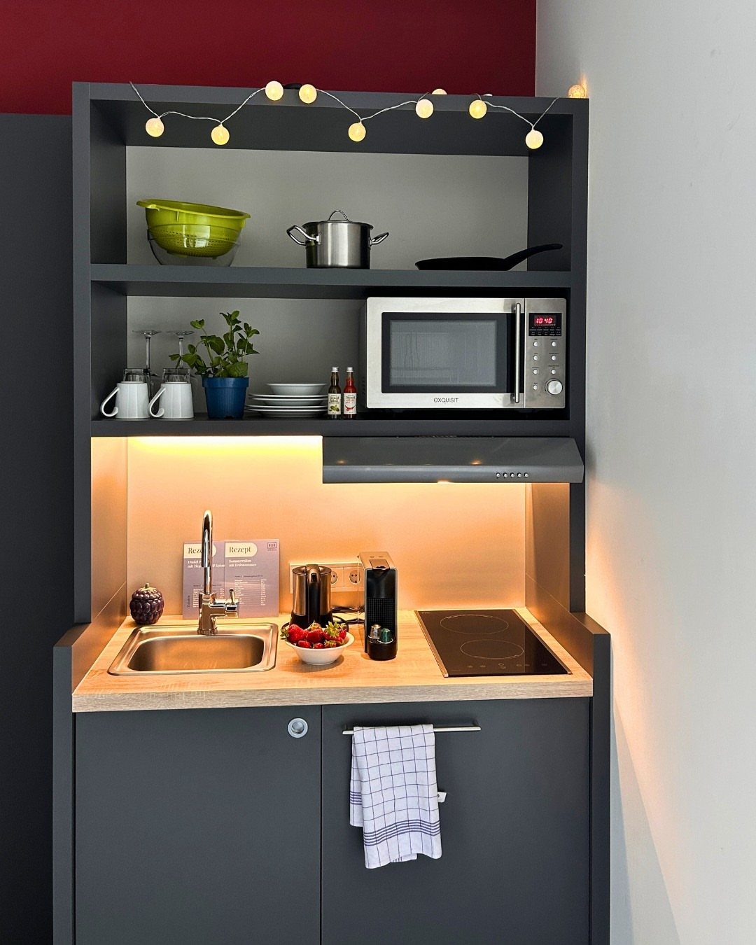 Tiny House Layout Ideas: 27 Smart Ways to Maximize Space 13 Compact dark grey kitchenette with wood countertop, microwave, sink, and open shelving.
