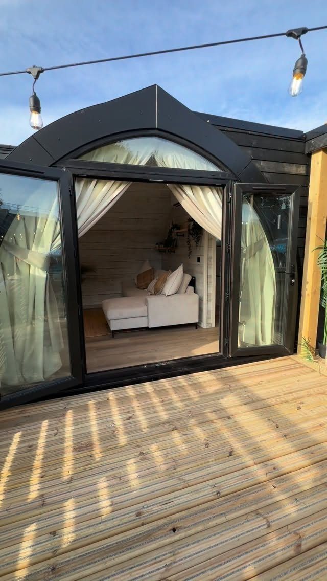 Tiny House Layout Ideas: 27 Smart Ways to Maximize Space 15 Wooden deck leading to open glass French doors of a tiny house.