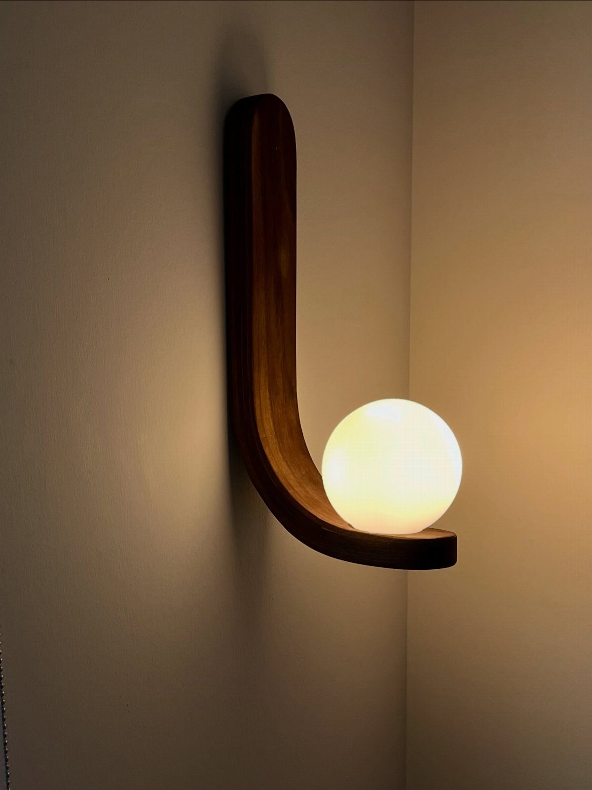 Tiny House Layout Ideas: 27 Smart Ways to Maximize Space 21 Modern wall-sconce light with a curved wooden base and glowing spherical bulb.