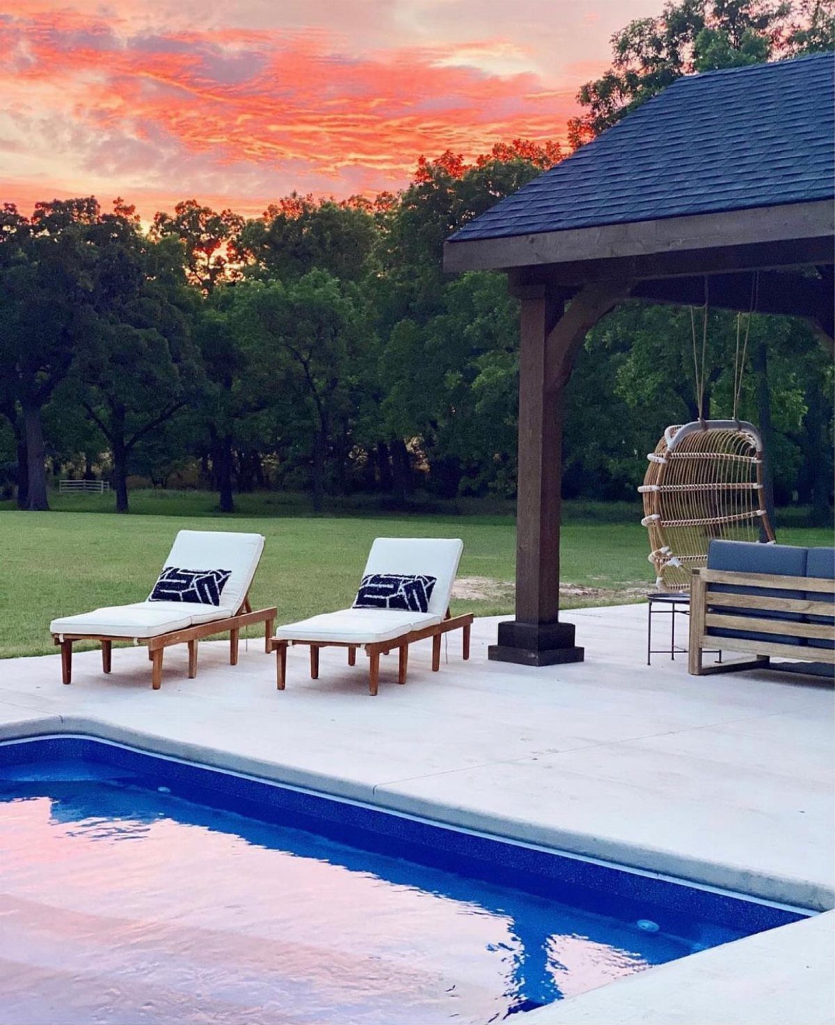 Wood Lounge Chair Ideas: 28 Styles from Teak to Mid-Century 4 Two wooden chaise lounges with white cushions by a swimming pool at sunset.