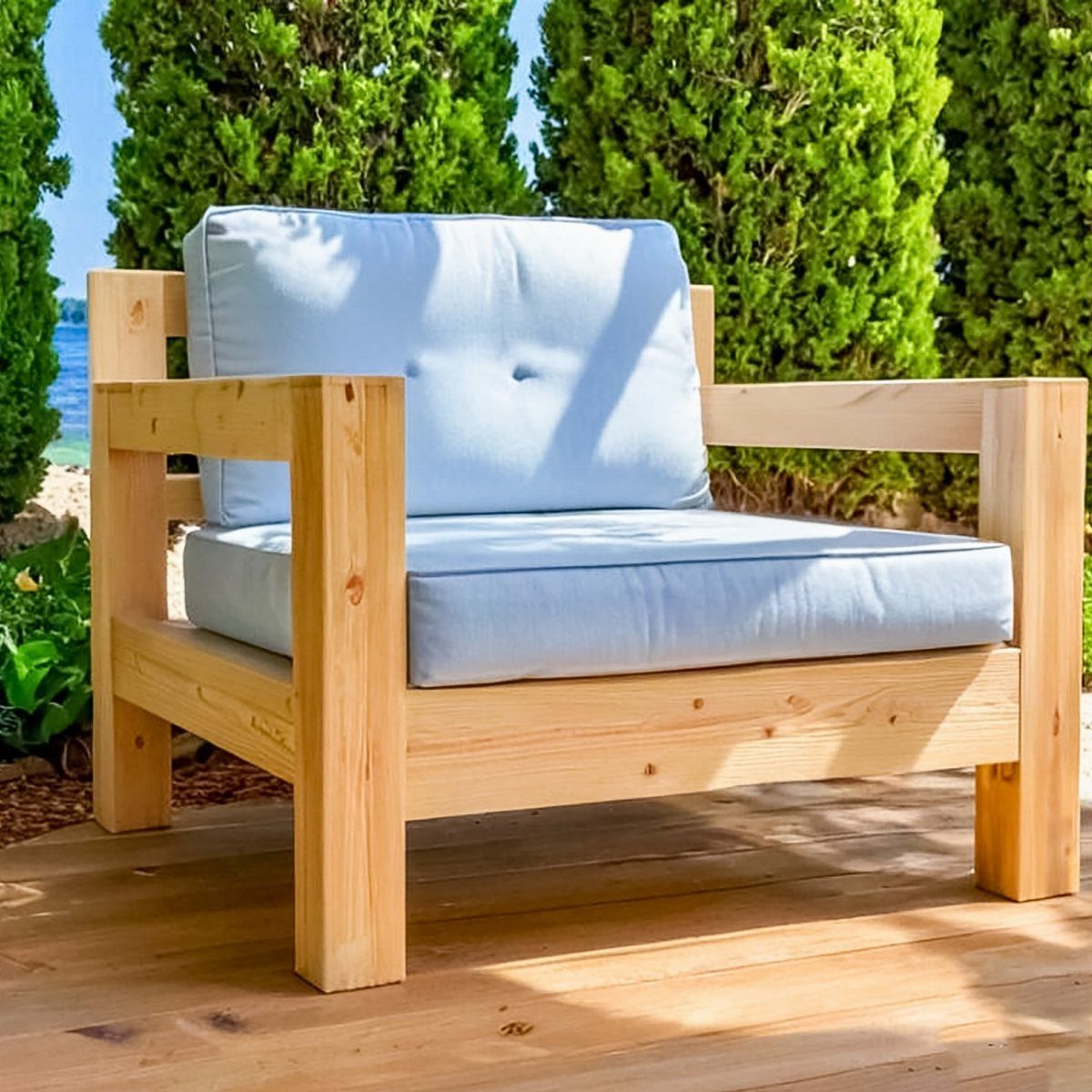 Wood Lounge Chair Ideas: 28 Styles from Teak to Mid-Century 22 Chunky light wood lounge chair with light blue cushions on a sunny wooden deck.