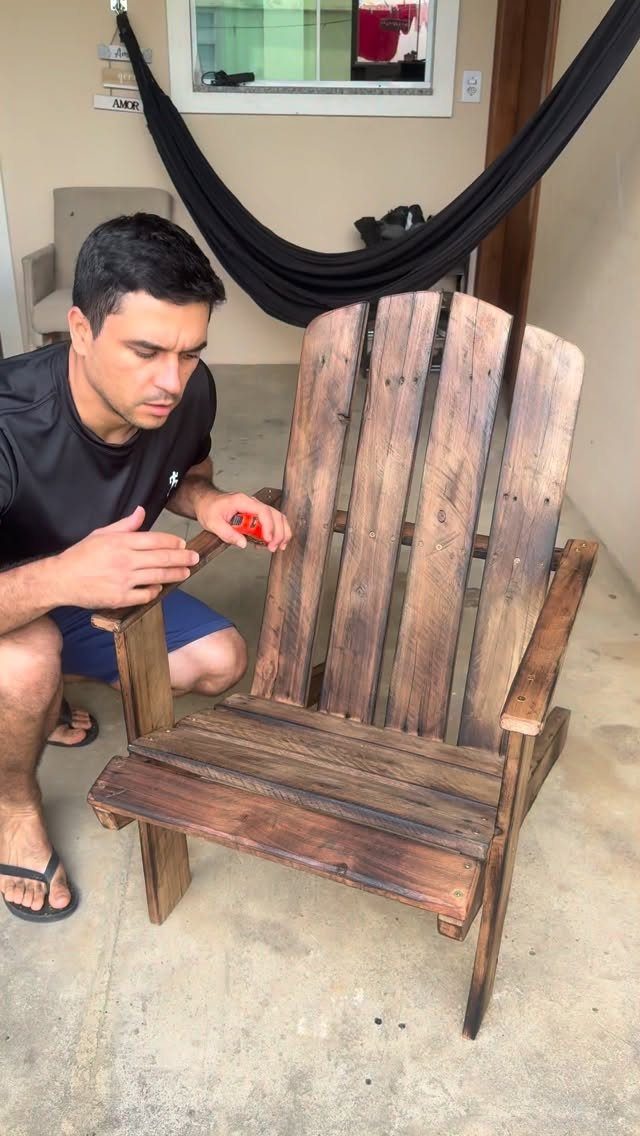 Wood Lounge Chair Ideas: 28 Styles from Teak to Mid-Century 18 Rustic dark-stained pallet wood lounge chair with a man crouching beside it.