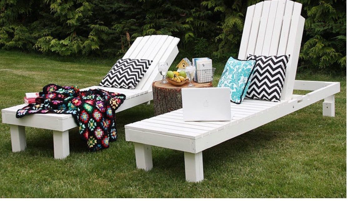 Wood Lounge Chair Ideas: 28 Styles from Teak to Mid-Century 6 Two white slatted wooden chaise lounges on a green lawn with colorful pillows.