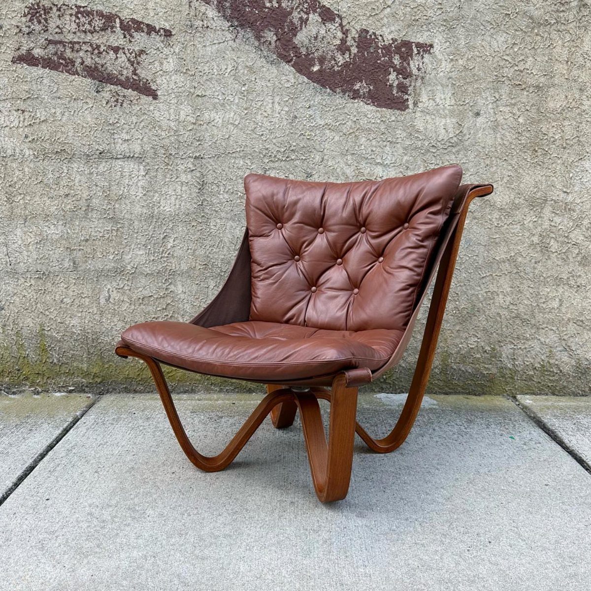 Wood Lounge Chair Ideas: 28 Styles from Teak to Mid-Century 10 Curved plywood lounge chair with brown tufted leather cushions against a concrete wall.